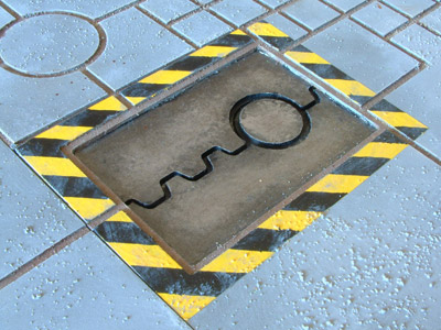 Close-up of the hatch in the street with warning stripes around it